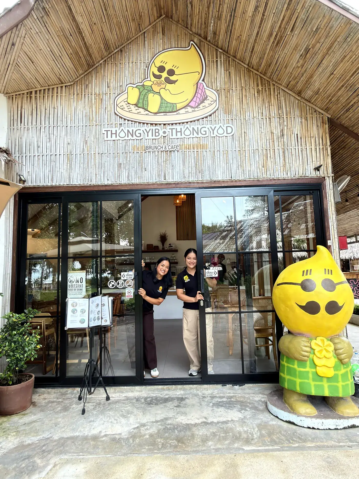 The twin founders of Thongyib Thongyod smiling at the cafe's front door