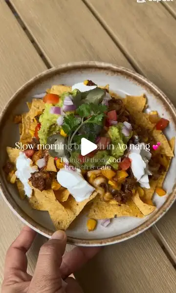 Loaded beef nachos with guacamole and sour cream on the wooden table — slow morning brunch video