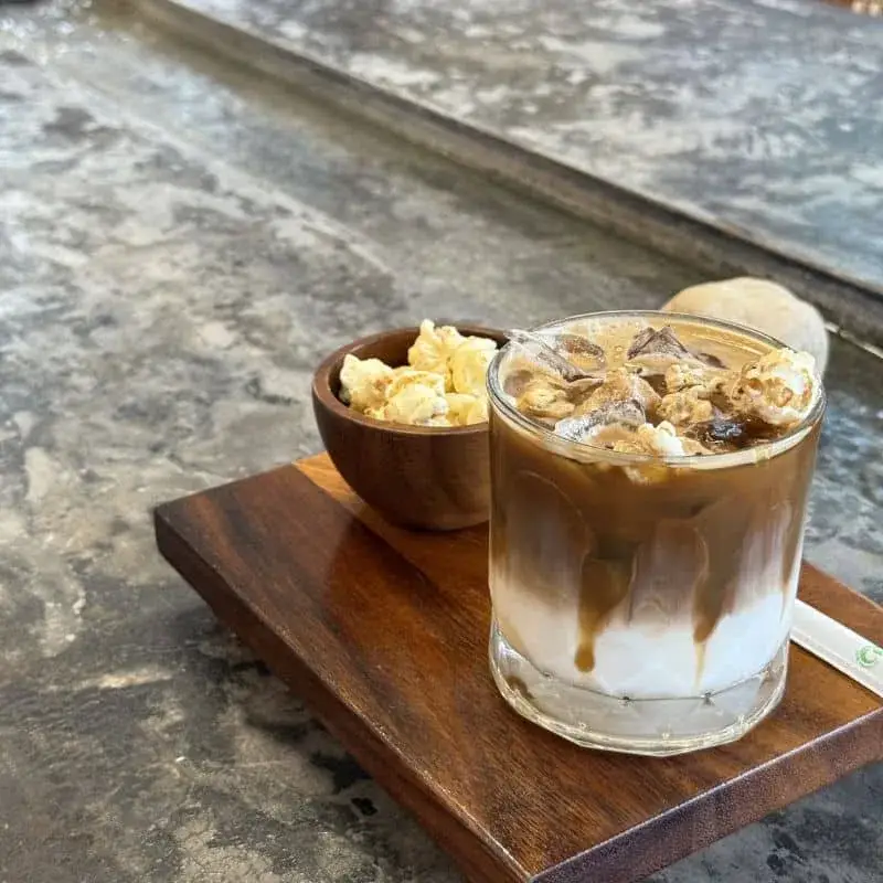 A croffle beside the cafe's Popular Coffee — caramel, popcorn and espresso — on the table