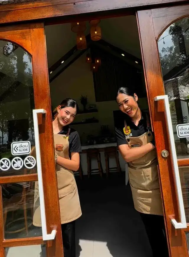 A smiling member of the Thongyib Thongyod team welcoming guests at the cafe