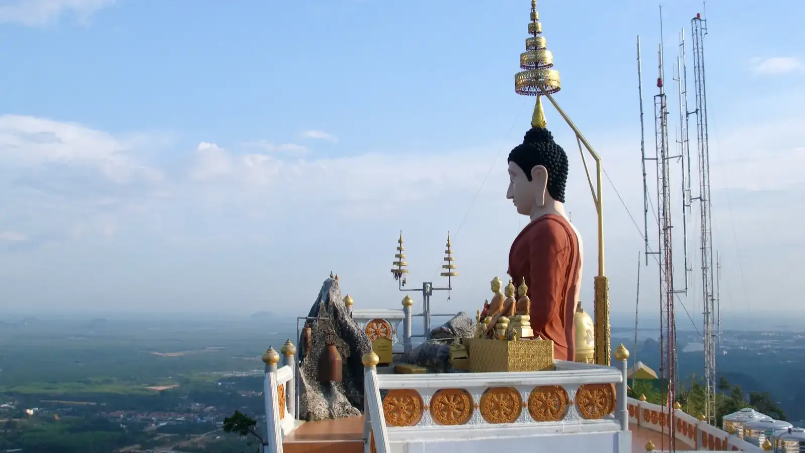 The golden Buddha and shrine on the summit of Tiger Cave Temple at dawn, with 360-degree views over Krabi's limestone hills and rice country below