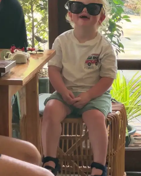 Little guest in oversized sunglasses laughing at a table inside Thongyib Thongyod cafe