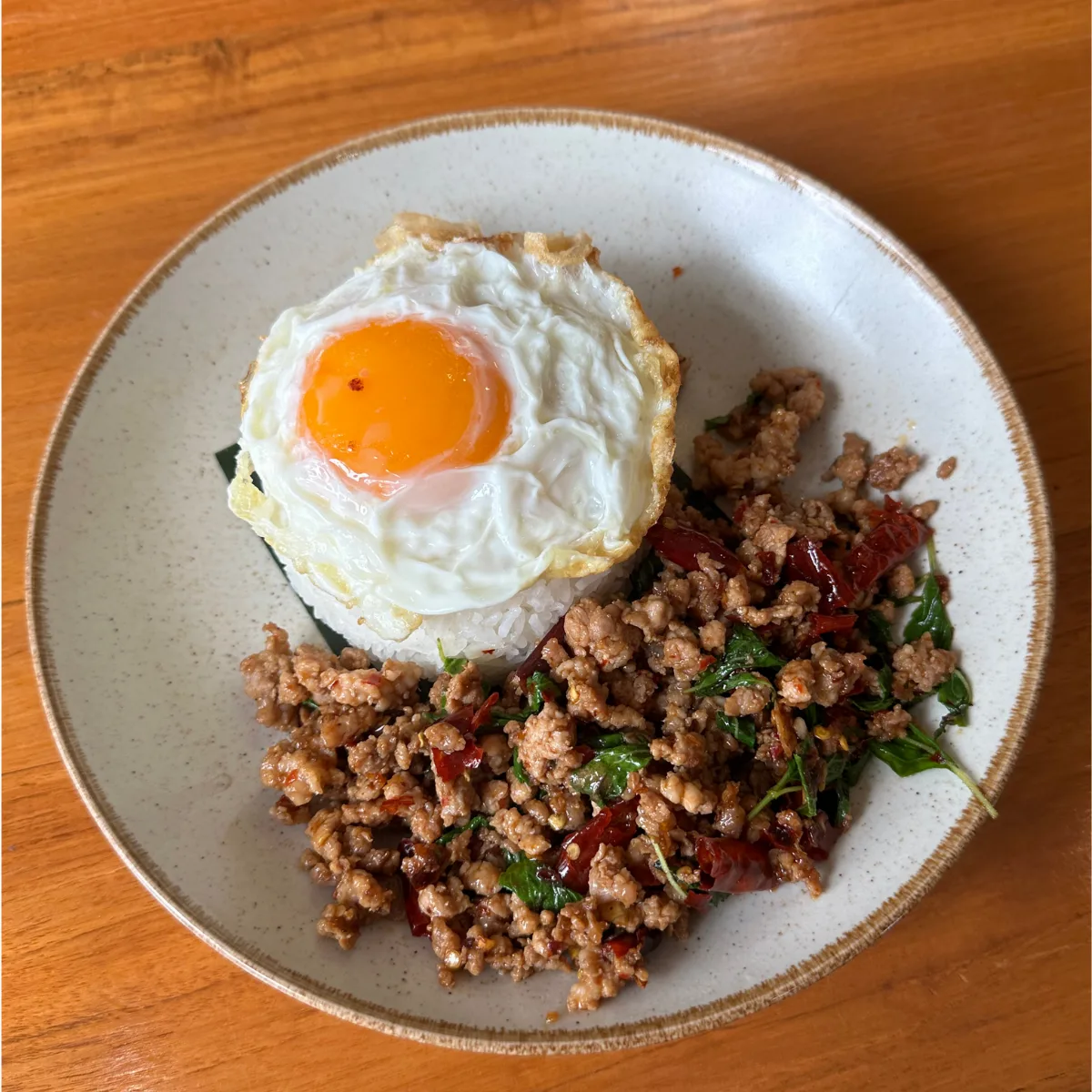Pad kra pao — minced pork stir-fried with holy basil and dried chilli over rice, topped with a crispy fried egg