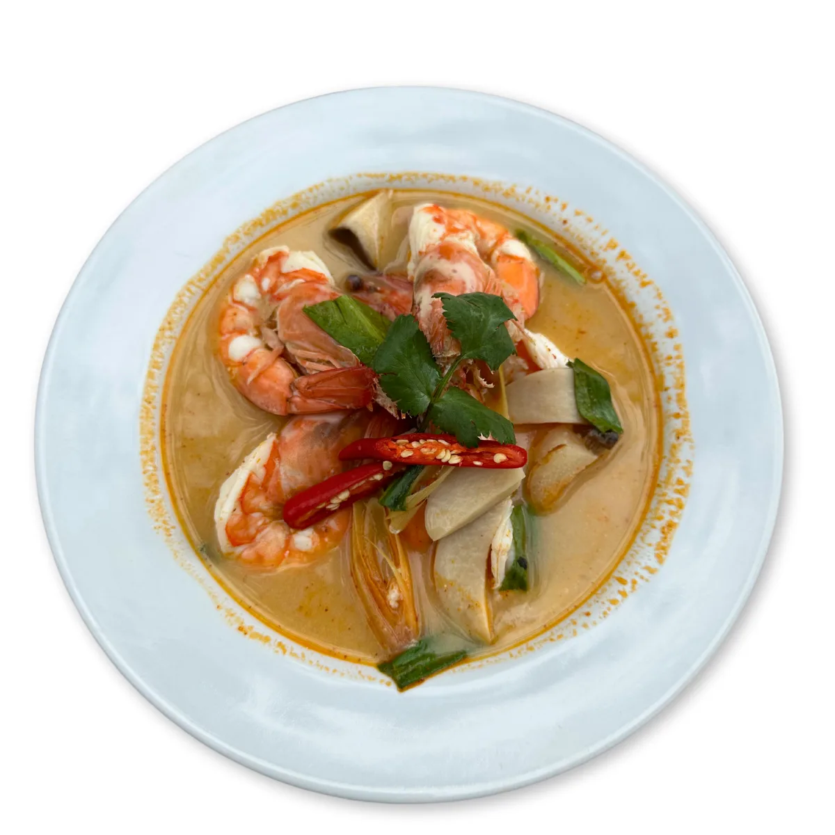A bowl of tom yum kung — hot-and-sour prawn soup with whole prawns, mushrooms, chilli and coriander